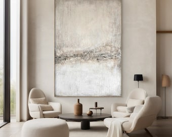 Op de afbeelding: Abstract schilderij in grijstinten en wit met een horizontale band van bruin en zwart in het midden. Het schilderij hangt aan een muur in een moderne woonkamer met twee witte fauteuils en een salontafel.