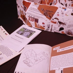 May include: A collection of small books with text about death and the process of embalming. The books are on a dark brown surface. One book has the title "Memento mori" and another has the title "What is embalming?"