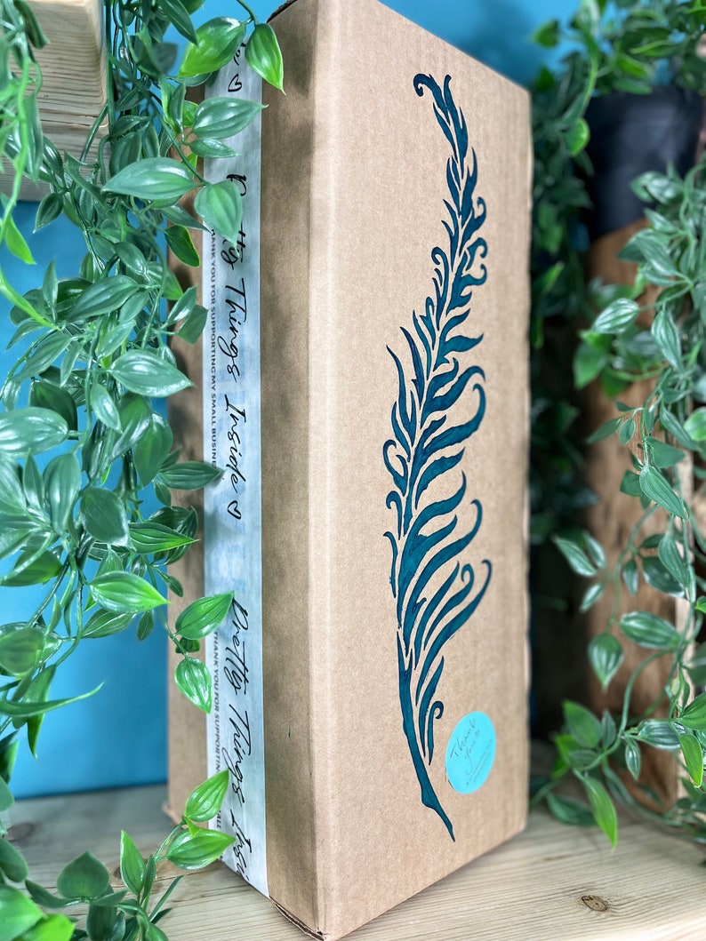 May include: A rectangular cardboard box with a teal feather design. The box has a white strip with the text "Pretty Things Inside" and "Thank you for supporting my small business". A teal sticker says "Thank you".