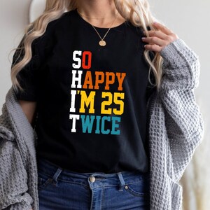 May include: Black t-shirt with a vintage-style graphic that reads "SO HAPPY I'M 25 TWICE". The text is in different colors, including red, yellow, blue, and green.