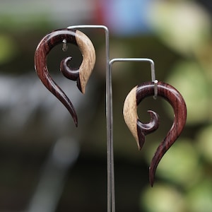 May include: A pair of wooden earrings with a swirl design. The earrings are made of two different types of wood, one dark brown and one light brown.