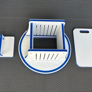 May include: A white wooden cutting board set with blue trim. The set includes a round base with the text "Redfield & Sons", a square cutting board with a handle, and a rectangular cutting board with a handle.