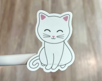 May include: White cat sticker with pink ears and a black outline. The cat is sitting with its tail curled around its legs. The sticker has the text "CAT LADY ALLEY" at the bottom.
