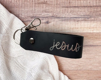 Llavero cristiano hecho de cuero negro con la escritura plateada "jesús"