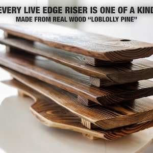 May include: A stack of handcrafted wooden risers made from Loblolly pine. Each live edge riser is unique, with a natural wood grain and a rich, dark brown finish. The text on the image reads: "EVERY LIVE EDGE RISER IS ONE OF A KIND MADE FROM REAL WOOD 'LOBLOLLY PINE'".