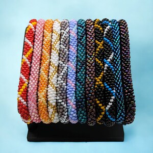 May include: A collection of colorful beaded bracelets in various patterns and colors, including red, orange, yellow, white, gray, blue, purple, and black.