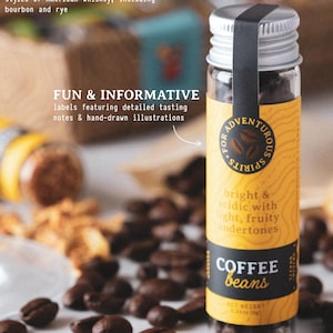 May include: A small glass bottle filled with coffee beans, featuring a yellow label with the text "COFFEE beans". The label also includes the text "bright & acidic with light, fruity undertones". The bottle is surrounded by coffee beans.