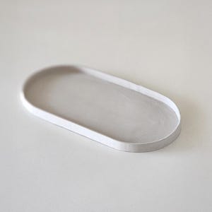 Può includere: Un vassoio ovale in ceramica bianca con una superficie liscia e leggermente strutturata.