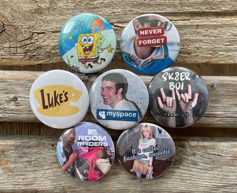 Op de afbeelding: Een verzameling van zeven ronde buttons met verschillende ontwerpen. E&eacute;n button toont SpongeBob SquarePants, een andere zegt "NEVER FORGET", en een derde heeft "SK8ER BOI" met handgebaren. Andere buttons zijn "Luke's" koffie, "myspace", "MTV Room Raiders" en "It's called fashion, sweetie."