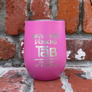 Op de afbeelding: Een felroze ge&iuml;soleerde tumbler met zilverkleurige tekst. De tekst luidt "WISH I WAS DRINKING TAB", met "TAB" in een groot lettertype en daaronder "GONE BUT NOT FORGOTTEN".