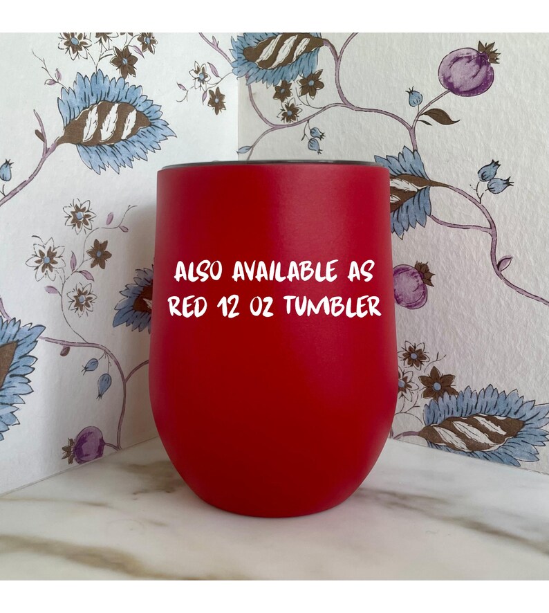 Op de afbeelding: Een helderrode 355 ml tumbler met een afgeronde basis. De tekst "ALSO AVAILABLE AS RED 12 OZ TUMBLER" staat in het wit. De tumbler staat tegen een bloemig patroon.