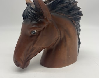 May include: A brown ceramic horse head planter with black mane and tail. The horse has a white star on its forehead and brown eyes.