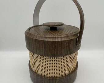 May include: A brown and beige ice bucket with a woven pattern and a silver handle. The bucket has a wood-grain design.