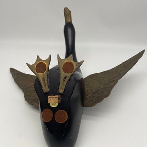 Puede incluir: Figurita de pato de madera negra con alas doradas y una etiqueta que dice "Wood Imports 92807 Made in Korea".