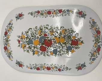 May include: White oval table mat with a floral design featuring red, yellow, and green leaves, lemons, mushrooms, and peppers. The text "Le Remarquable" is printed on the right side of the mat.