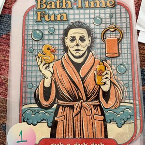 May include: A rectangular print featuring a masked figure in an orange bathrobe holding a yellow rubber duck and a pumpkin-labeled soap bottle. The text reads Bath Time Fun and rub-a-dub-dub. The background shows a tiled wall, bubbles, and a towel.