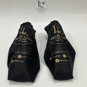 May include: Two black fabric drawstring bags featuring the gold printed logo and text Leather Lords Handcrafted Leather Products, along with social media icons and website information. A circular logo is positioned above the two bags.