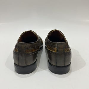 Puede incluir: Un par de zapatos de vestir de cuero gris oscuro con un panel texturizado con relieve de cocodrilo en los laterales y el tal&oacute;n. Los zapatos tienen un borde perforado estilo brogue, un tac&oacute;n bajo y un acabado liso y pulido.