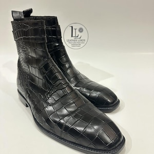 May include: A pair of black leather ankle boots with a crocodile skin texture. The boots have a square toe and a small heel. The Leather Lords logo is visible in the background.