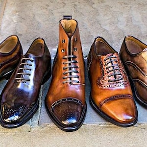 May include: A collection of seven leather dress shoes and one leather boot arranged in a row. The footwear features various shades of brown and black, with polished finishes, lace-up closures, and decorative brogue detailing on several pairs.