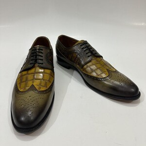 Puede incluir: Un par de zapatos oxford tipo wingtip con dise&ntilde;o bicolor, que presenta un empeine de cuero color amarillo mostaza con relieve de cocodrilo y detalles en cuero verde oliva oscuro. Incluyen cordones negros, detalles brogue y tac&oacute;n bajo.