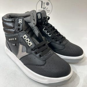 Könnte beinhalten: Ein Paar schwarze High-Top-Sneaker mit weißen Sohlen. Die Sneaker haben ein perforiertes Design auf der Zehenbox und einen grauen Akzent an der Seite. Die Schnürsenkel sind schwarz und die Zunge ist grau. Der Markenname "Leather Lords" ist in einem kreisförmigen Logo zu sehen.