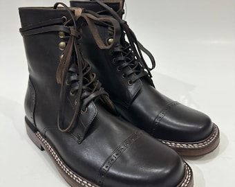 May include: A pair of dark brown leather lace-up boots featuring a rounded toe, a decorative brogue-style perforated cap toe, and brass-toned eyelets. The boots have a thick, stacked wooden-look sole with prominent white contrast stitching.