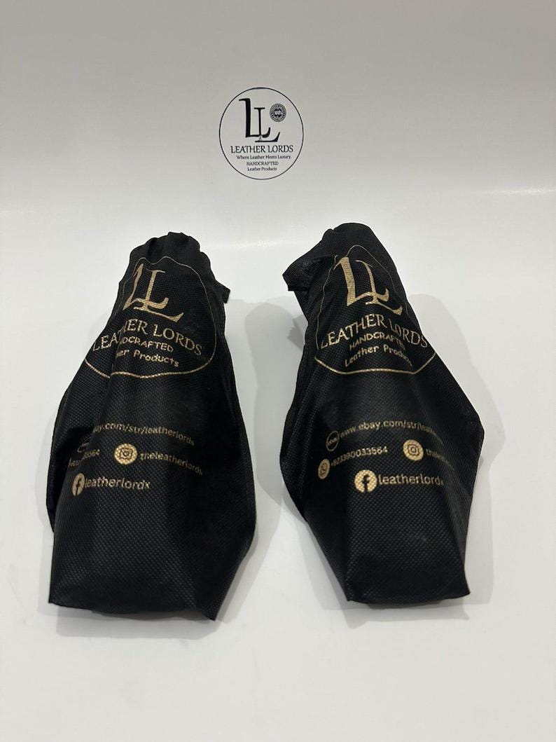 May include: Two black fabric drawstring bags featuring the gold printed logo and text Leather Lords Handcrafted Leather Products, along with social media icons and website information. A circular logo is positioned above the two bags.