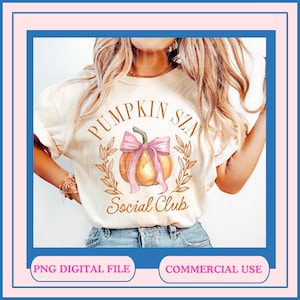 Op de afbeelding: Een wit T-shirt met een gouden en roze grafisch ontwerp met een pompoen met een roze strik en de tekst "Pumpkin Szn Social Club".