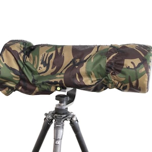 May include: A camouflage lens cover for a camera lens mounted on a black tripod.