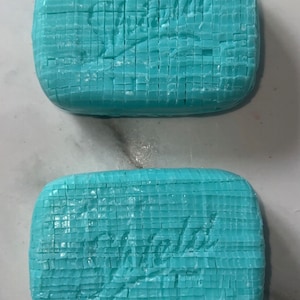 Puede incluir: Dos barras de jabón azul claro con la palabra "Violets" en relieve en cada barra.