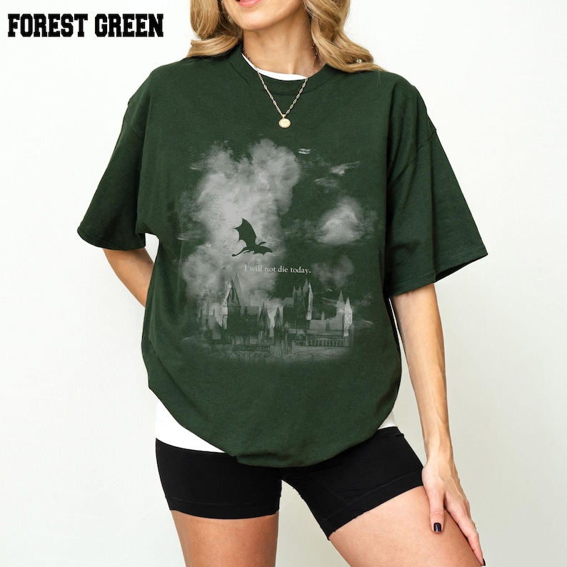 May include: Forest green t-shirt featuring a dragon and castle graphic with the text "I will not die today." The dark green shirt has short sleeves. The t-shirt is made of a soft material and is a comfortable fit.