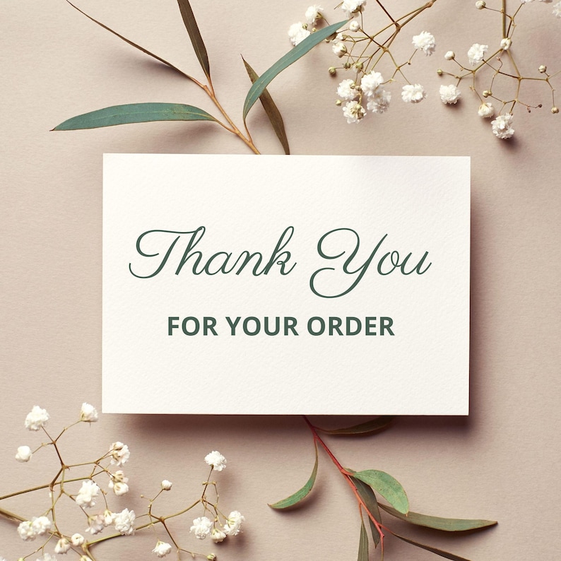 Puede incluir: Una tarjeta blanca con las palabras "Thank You FOR YOUR ORDER" en elegante escritura verde. La tarjeta est&aacute; rodeada de ramitas de flores blancas y hojas verdes, sobre un fondo neutro.