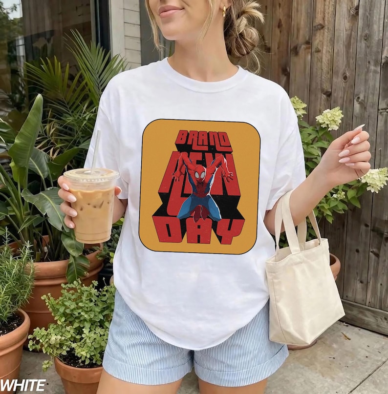 Puede incluir: Camiseta blanca con un gr&aacute;fico retro de Spider-Man y las palabras "BRAND NEW DAY" en rojo y naranja. La camiseta es de cuello redondo.