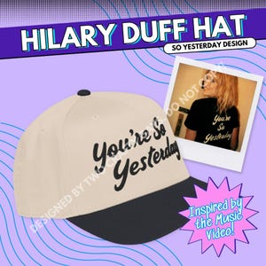 May include: A beige and black baseball cap featuring the text "You're So Yesterday" in black script. The cap has a black peak and a small black button on top. The image also includes a photo of a person wearing a black t-shirt with the same text.