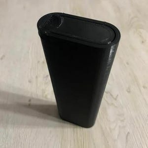 Op de afbeelding: Een zwarte, rechthoekige container met afgeronde randen. De container heeft een getextureerd oppervlak en een deksel met een gebogen inkeping. Het item is waarschijnlijk een opbergdoos of een vergelijkbaar product.