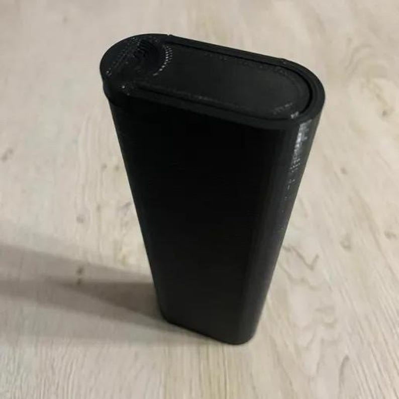Op de afbeelding: Een zwarte, rechthoekige container met afgeronde randen. De container heeft een getextureerd oppervlak en een deksel met een gebogen inkeping. Het item is waarschijnlijk een opbergdoos of een vergelijkbaar product.