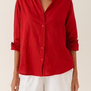 K&ouml;nnte beinhalten: Ein leuchtend rotes Hemd mit Stehkragen und langen &Auml;rmeln, die hochgekrempelt sind. Das Hemd hat eine Knopfleiste und wird mit wei&szlig;en Shorts kombiniert. Der Stoff wirkt leicht.