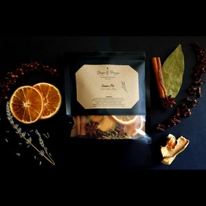 May include: A black pouch with a white label that reads "Sage & Freya" and "Simmer Pot" with a list of ingredients. The pouch contains dried fruit, spices, and herbs.