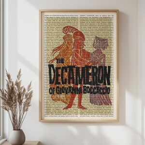 May include: A framed print of "The Decameron" by Giovanni Boccaccio. The artwork features three stylized figures in shades of orange and purple against a backdrop of text. The title is prominently displayed in bold black letters.