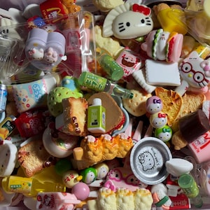 May include: A collection of miniature food-themed toys and Hello Kitty accessories, including small plastic sandwiches, bottles, snacks, and character-shaped items, some packaged in clear plastic bags, featuring various colors and textures.