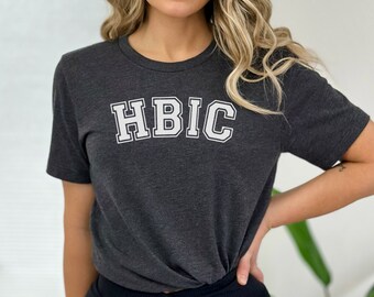 May include: A dark gray t-shirt with a white graphic that says "HBIC" in a varsity style font.