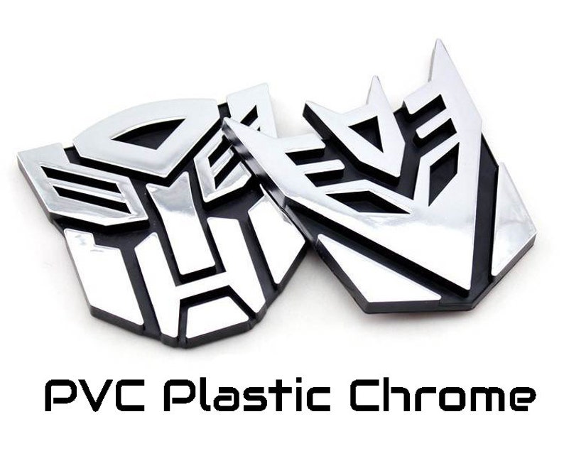 May include: Two chrome-finished PVC plastic emblems, featuring a stylized geometric design. The emblems have a shiny, reflective surface and are set against a white background. The text "PVC Plastic Chrome" is displayed below the emblems.