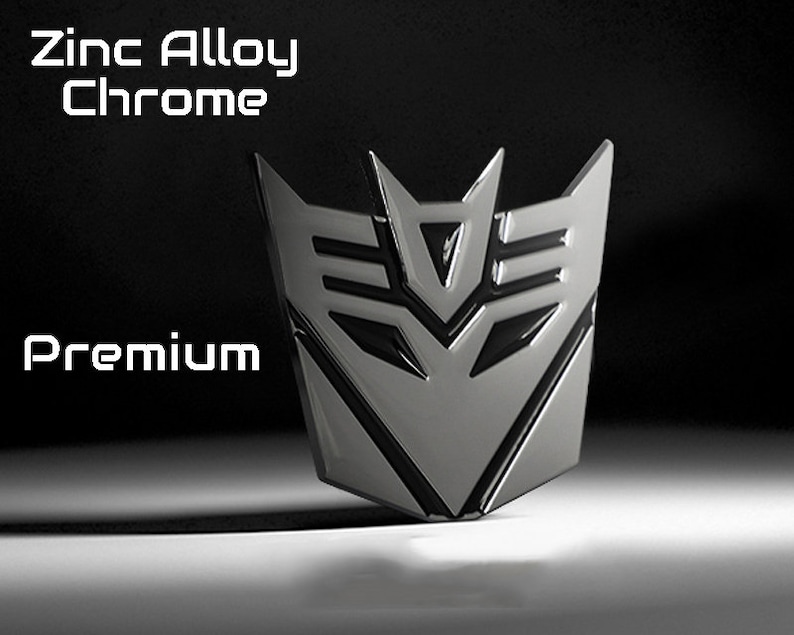 May include: A chrome-finished emblem with a geometric design, featuring the text "Zinc Alloy Chrome" and "Premium". The emblem has a metallic sheen and is set against a dark background.