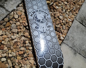 May include: Black and white skateboard deck with a honeycomb pattern and a skull graphic with the text "KRAWN" around it.