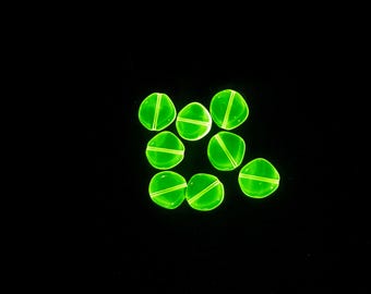 May include: Eight translucent, neon green, flat-sided beads with a diagonal and horizontal line design. The beads are scattered against a black background. These beads are ideal for jewellery making.