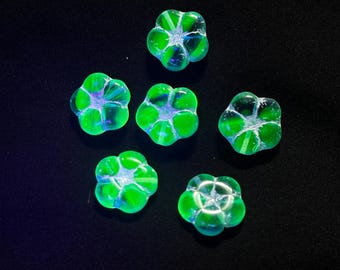 May include: Six small, five-petaled flower-shaped beads made of translucent glass. Each bead features a vibrant, glowing neon green hue with a subtle iridescent sheen and a star-like pattern radiating from the centre hole of the flower.