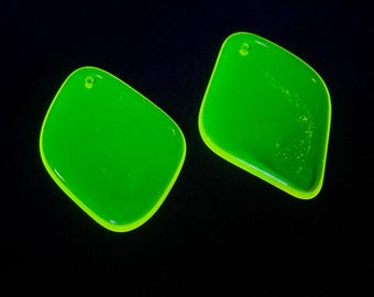 May include: Two bright neon green diamond-shaped pendants with smooth, translucent surfaces. Each piece features a small circular hole near the top corner, designed for attachment to jewellery findings or cords, set against a dark background.