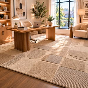 May include: A large area rug featuring a textured, geometric pattern in shades of beige and cream. The design consists of various shapes, including rectangles, squares, and semi-circles, with alternating smooth and high-pile tufted surfaces.