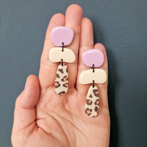 Boucles d'oreilles suspendues en argile polymère motif Cailloux Leo trois pièces crème noir lilas formes géométriques asymétriques bouchon en acier inoxydable Cheetah Bttm. middle Pebbles